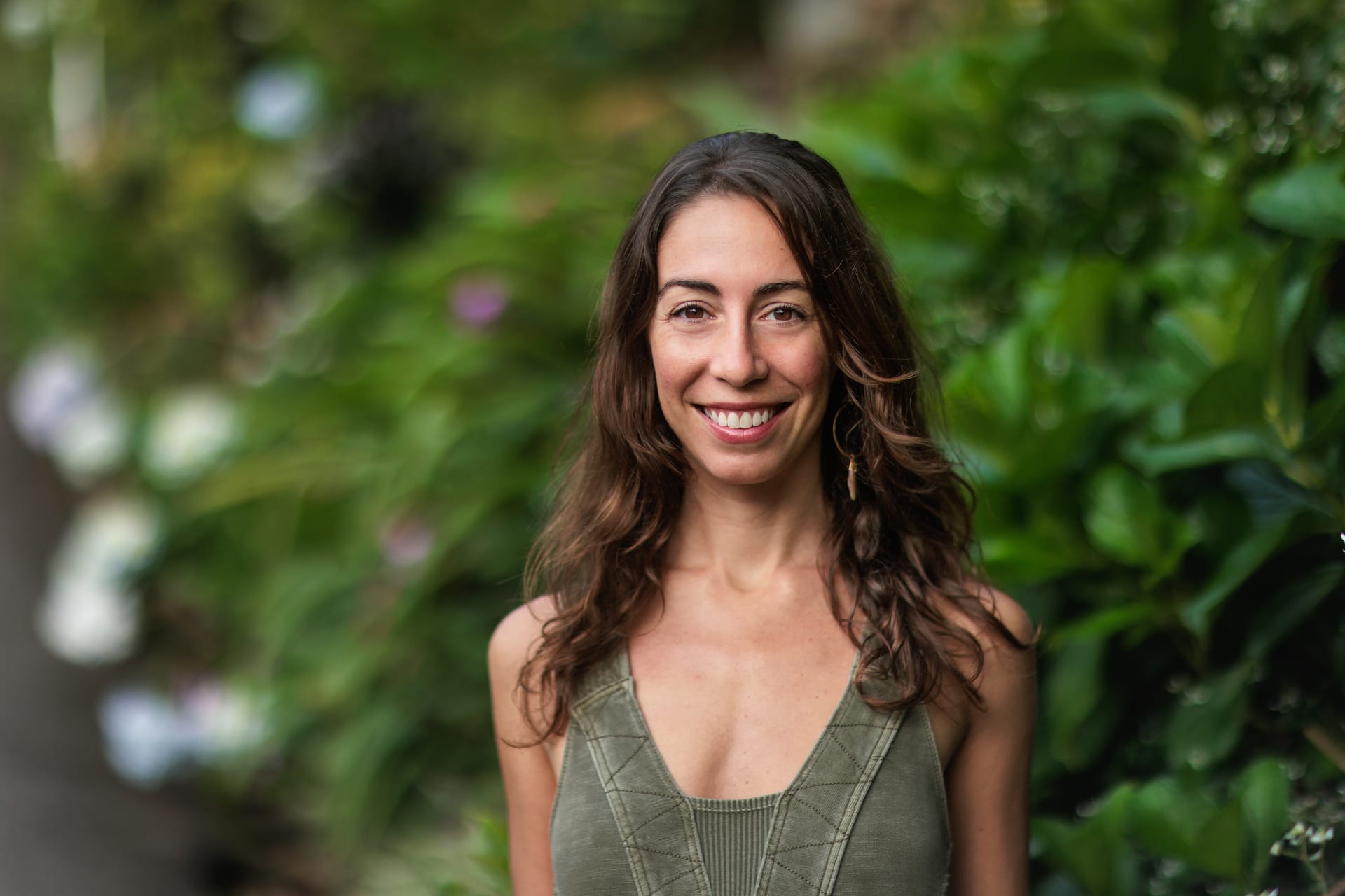 Woman with long wavy brown hair smiling in front of green plants in Costa Rica