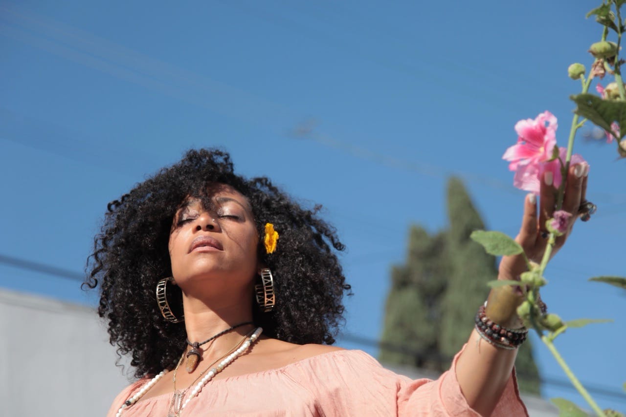 Woman with eyes closed, natural hair, holding a flower, conducting a ceremony